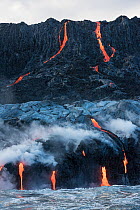 Hot lava from the 61G flow, emanating from Pu'uu O'o on Kilauea Volcano, flows over sea cliffs and into the ocean through lava tubes at the Kamokuna ocean entry in Hawaii Volcanoes National Park, Kala...