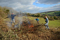 Volunteers burning scrub they've cleared from a grassland hillside to improve habitat for bees and other pollinators for Buglife / Avon Wildlife Trust's West of England B-Lines project, Bath and north...