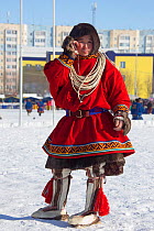 Young Nenets man on a mobile phone wearing traditional reindeer skin clothing during the reindeer herders' festival at Nadym. Yamal, Western Siberia, Russia