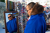 Nenets man trying on sunglasses at a stall at the reindeer herders' festival in Nadym. Yamal, Western Siberia, Russia