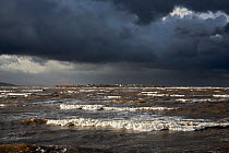Hilbre Island viewed at high tide with gathering storm clouds from  Hilbre Point at the mouth of the Dee Estuary, Wirral, UK, January.