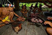Mentawai man dividing cooked pork, Siberut Island, Sumatra. July 2016.