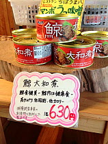 Canned whale meat for sale at a souvenir shop for tourists in Japan. The label states that the contents are from an unspecified baleen whale. The sales sign states that whale meat is a food that is go...