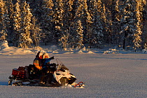Nils-Torbjorn Nutti, owner and operator at Nutti Sami Siida, and Klara Enbom-Burreau on snowmobile trip into the wilderness, Jukkasjarvi, Lapland, Laponia, Norrbotten county, Sweden Model released.