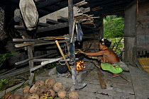 Mentawai woman cooking Sago in banana leaf, Siberut Island, Sumatra.  July 2016.