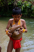 Young Sumatran boy with Sunda pangolin (Manis javanica) they have caught, Sumatra. July 2016.