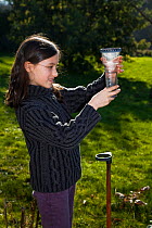 Young girl checking a rain gauge in a garden. Brittany. France. Model released