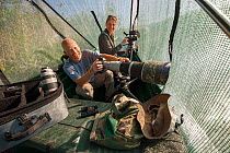 Wildlife Photographer Ingo Arndt and Videographer Silke Arndt working from camouflage boat to photograph birds, Danube Delta, Romania, June 2015.