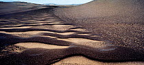 Black sands over-laying the beige sand dunes of the Skeleton Coast, forming wind-blown patterns near the coast.