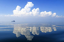 Small boat on calm waters with reflections of cloud formations, Gulf of Thailand, Pacific.