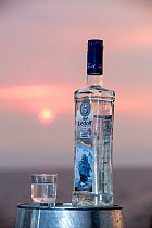Vodka bottle and glass at sunset, Lake Baikal, Siberia, Russia, June.