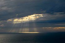 Rays of sunshine breaking through dark clouds over sea,  English Channel, Kent, UK. July