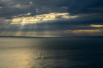 Rays of sunshine breaking through dark clouds over sea of English Channel, Kent, UK. July