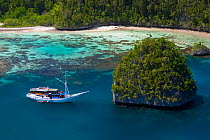 Bugis schooner, live-aboard dive vessel, at anchor in a limestone island lagoon, Uranie Island, Raja Ampat, West Papua, Indonesia.