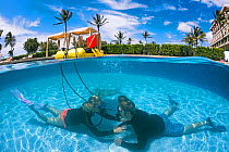 Two divers practices their diving skills in a resort pool, Hawaii. December 2013.  Model released.