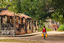Boy carrying jugs of water past a building destroyed during the civil war on Ibo Island, in the Quirimbas Archipelago, Mozambique. June 2011