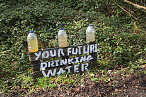 Bottles of dirty water at oil drilling and fracking protest camp, Leith Hill, Surrey, UK. March, 2017