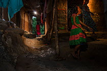 Women and girl walking through urban alley. Aarey Milk Colony in unofficial buffer zone of Sanjay Gandhi National Park, Mumbai, India. January 2016