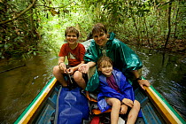 Orangutan researcher Cheryl Knott and children ride boat down river from Cabang Panti Research Station, Gunung Palung National Park, Borneo. August 2010 Model released.