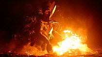 Slow motion clip of a Baining man performing fire-dance ceremony, kicks at fire, Baining Mountains, East New Britain, Papua New Guinea.  2017.
