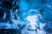 Woman walking in an ice cave below the Breidamerkurjokull Glacier, eastern Iceland. February 2015. Model released.