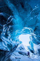 Woman exploring ice cave below the Breidamerkurjokull Glacier, eastern Iceland, February.