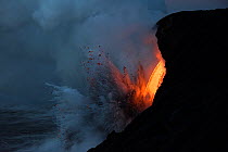RF - Hot lava from the 61G flow from Kilauea Volcano entering the ocean from the open end of a lava tube at the Kamokuna entry in Hawaii Volcanoes National Park in the pre-dawn, causing steam explosio...
