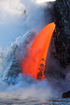 Hot lava from the 61G flow from Kilauea Volcano entering the ocean from the open end of a lava tube at the Kamokuna entry in Hawaii Volcanoes National Park, producing violent steam explosions, Kalapan...