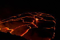 Molten lava boils at night in a lava lake in a pit below the crater floor of Halemaumau Crater, Kilauea Volcano, Hawaii. Red-orange jagged lines are junctures between plates of hard cooled lava floati...