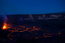 Hot lava fountains at a subduction zone at the edge of a lava lake, covered by plates of partially solidified cooled lava floating on its surface, in a pit within Halemaumau Crater, Kilauea Volcano, H...