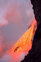 Hot lava from the 61G flow from Kilauea Volcano gushing into the Pacific Ocean from the open end of a lava tube at the Kamokuna entry in Hawaii Volcanoes National Park, producing a great cloud of stea...