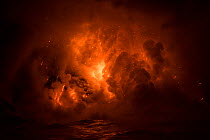 Hot lava from the 61G flow from Kilauea Volcano entering the ocean from the open end of a lava tube at the Kamokuna entry in Hawaii Volcanoes National Park, producing a great cloud of steam, and causi...
