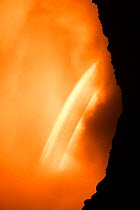 Hot lava from the 61G flow from Kilauea Volcano enters the ocean from the open end of a lava tube at the Kamokuna entry in Hawaii Volcanoes National Park, producing a great cloud of steam; a slow came...