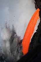 Close up of hot lava from the 61G flow from Kilauea Volcano entering the ocean from the open end of a lava tube at the Kamokuna entry, producing steam explosions, Hawaii Volcanoes National Park, Kalap...