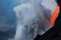 Hot lava from the 61G flow from Kilauea Volcano entering the ocean from the open end of a lava tube at the Kamokuna entry, producing steam explosions that carry pumice rocks high into the air and rele...