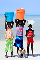 Portrait of three girls, with containers on head  to collect water, and dog, Orango Island, Bijagos UNESCO Biosphere Reserve, Guinea Bissau, February 2015.
