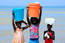 Portrait of three girls with containers on head  to collect water, Orango Island, Bijagos UNESCO Biosphere Reserve, Guinea Bissau, February 2015.