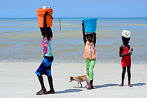 Girls walking along beach on way to collect water.  Orango Island, Bijagos UNESCO Biosphere Reserve, Guinea Bissau, February 2015.