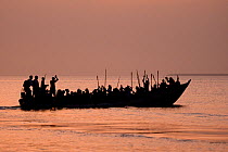 Boat full of carnival participants arriving at sunset, Eticoga Carnival, Orango Island, Bijagos UNESCO Biosphere Reserve, Guinea Bissau, February 2015.