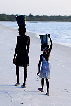 Two girls on their way along beach to collect water, Orango Island, Bijagos UNESCO Biosphere Reserve, Guinea Bissau, February 2015.