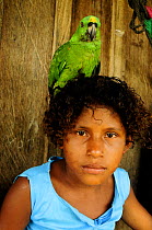 Girl with pet Yellow-naped parrot (Amazona auropalliata) perched on her head, Rio Platano Biosphere Reserve and UNESCO World Heritage Site, La Mosquitia, Honduras.