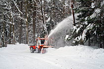 Holder C9700H municipal tractor with snow blower clearing snow from road in forest after heavy snowfall in winter, Bavarian Forest, January 2017.