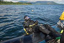Diver undertaking a backward roll off side of boat, Lamlash Bay, Isle of Arran, South Arran Marine Protected Area, Scotland, UK, August 2016.