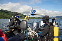 Two divers undertaking their final checks on dive boat, Lamlash Bay, Isle of Arran, South Arran Marine Protected Area, Scotland, UK, August 2016.
