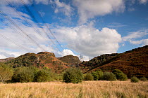 Power lines and pylons carrying electricity over mountain landscape from hydroelectric power station at Maentwrog, Wales, UK, October 2016.