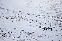 Group of hikers with backpacks for overnight camping, Cairngorms National Park, Scotland, UK, February 2016.