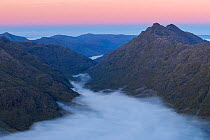 Mountain peaks of Sgurr na h-Aide and Carn Mor  above temperature inversion in Glen Dessary, Knoydart at sunrise. Taken from Sgurr Cos na Breachd-laoidh, Lochaber, Scotland, UK, October 2016.