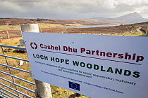 Sign on gate to major woodland restoration project run by Cashel Dhu Partnership, with Loch Hope and Ben Hope in background, Sutherland, Scotland, UK,