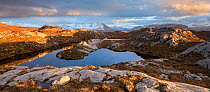 Remote hill lochan with view towards Loch Torridon and Ben Damph, in late winter light, Wester Ross, Scotland, UK, March  2017