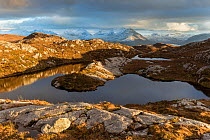 Remote hill lochan with view towards Loch Torridon and Ben Damph, Wester Ross, Scotland, UK, March  2017